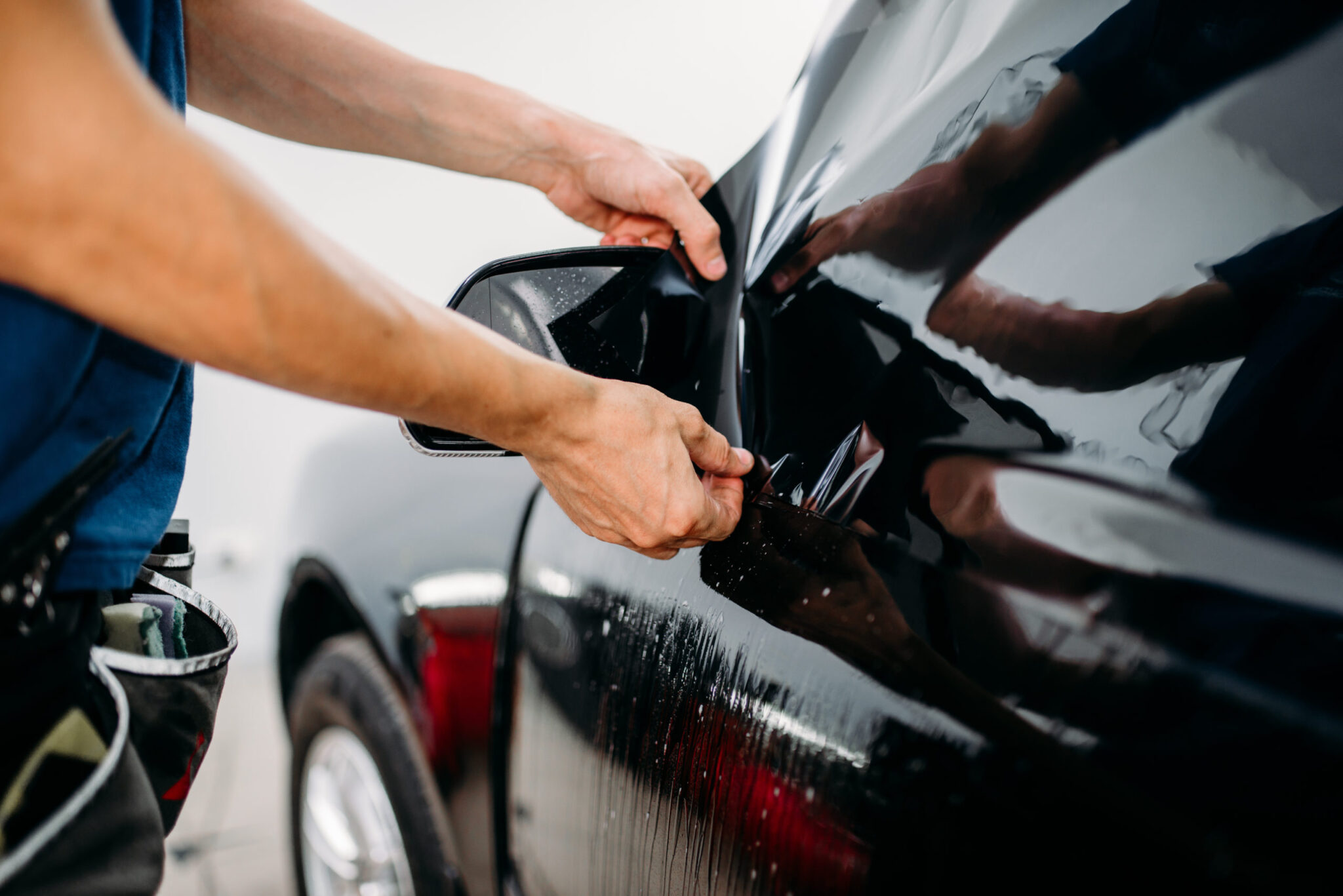 man installing window tint on car
